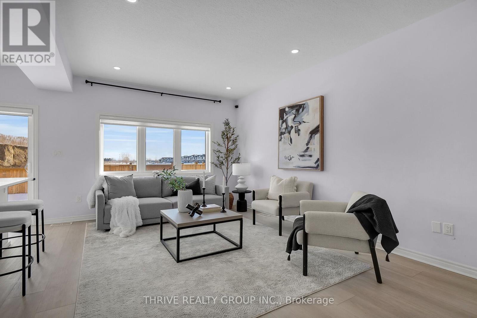 A well-lit living room with a large window, a grey sofa, a coffee table, and a rug.