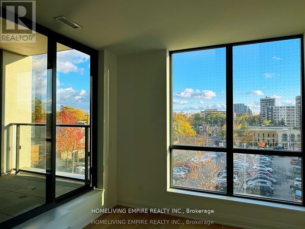 A room with a view of a parking lot and buildings outside.