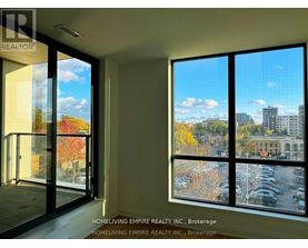 A room with a view of a parking lot and buildings outside.