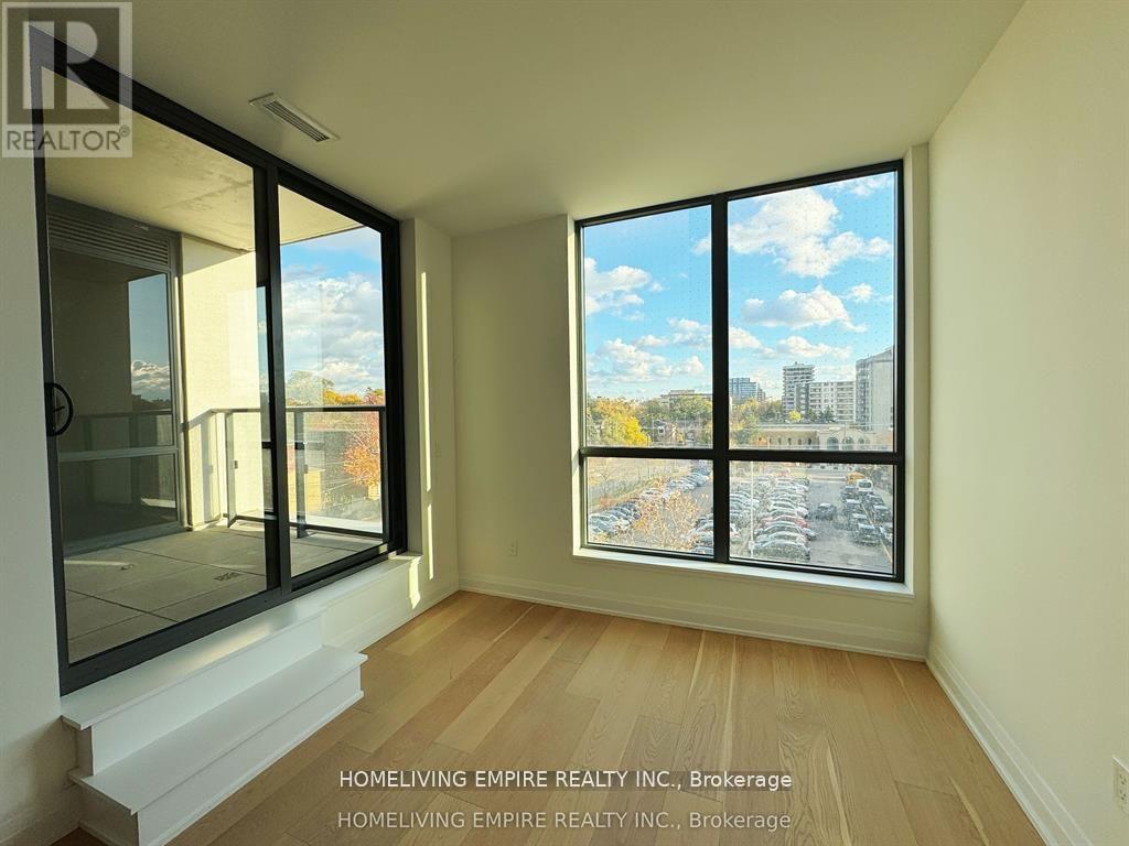A room with a view of a parking lot and buildings outside the window.