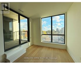 A room with a view of a parking lot and buildings outside the window.