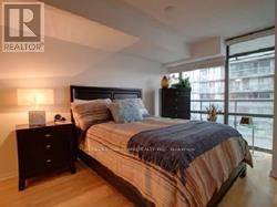 A bedroom with a bed, nightstand, and lamp.