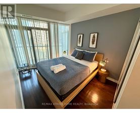 A bedroom with a bed, nightstand, and window.