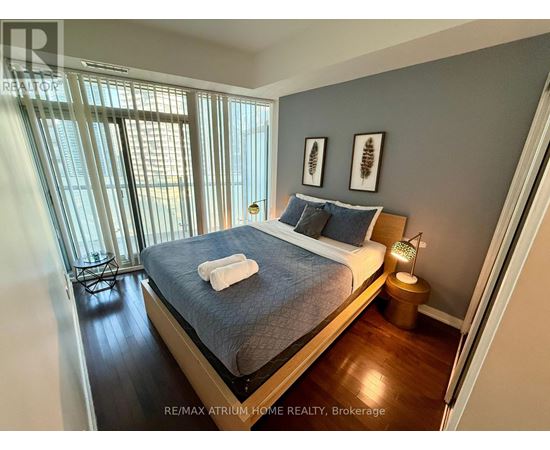 A bedroom with a bed, nightstand, and window.