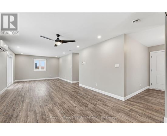 A spacious room with wooden flooring and a ceiling fan.