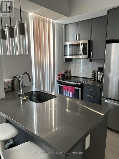 A modern kitchen with a stainless steel countertop and a microwave above the oven.