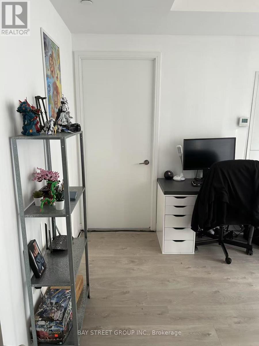 A room with a desk, chair, and shelves with various items.