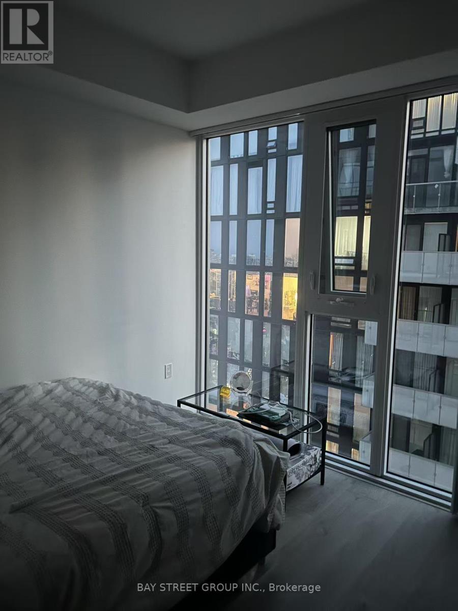 A bedroom with a large bed and a view of a cityscape through the window.