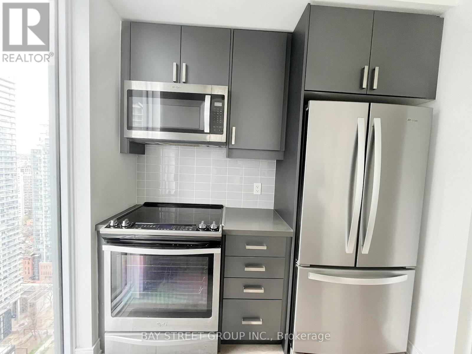 Two white Whirlpool washing machines stacked in a cabinet.