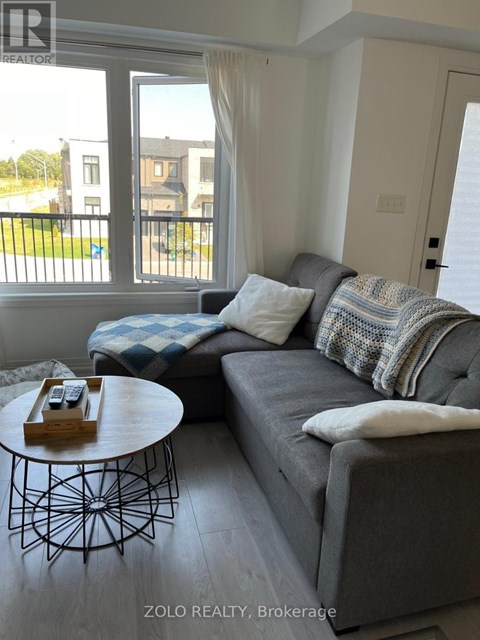 A living room with a grey couch and a round table with a wooden tray on it.
