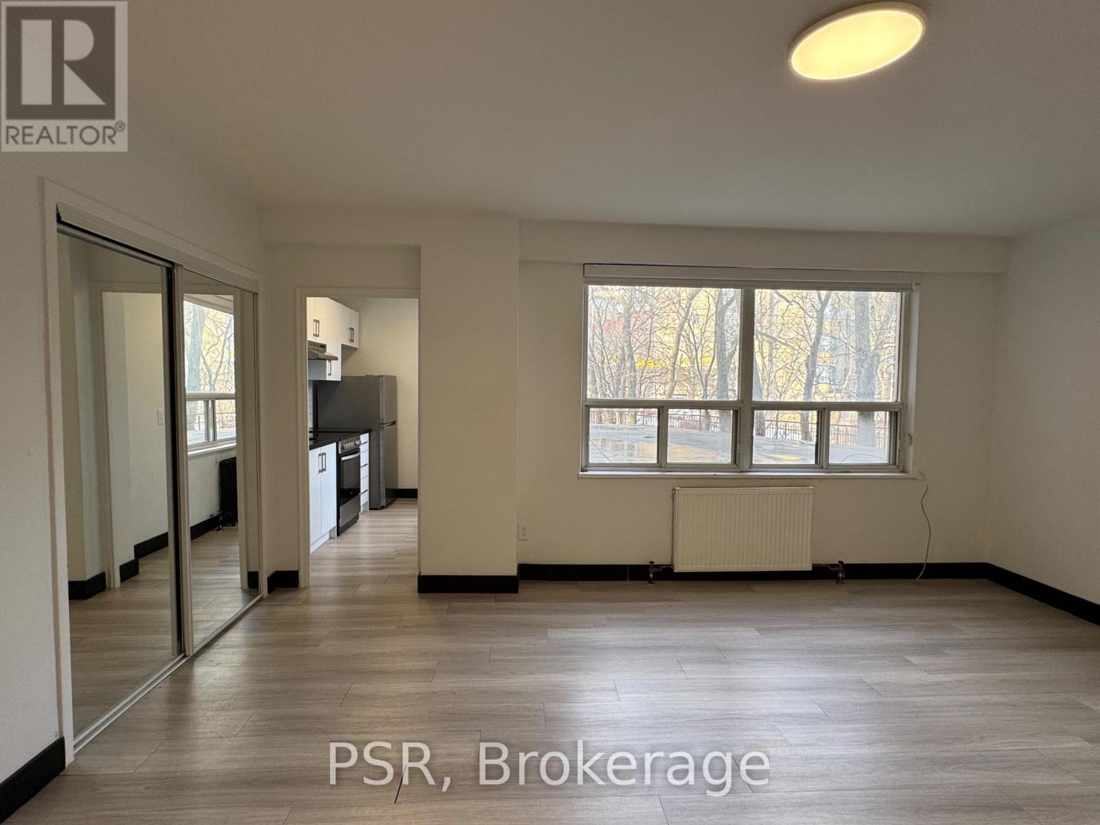 A spacious room with a large window and a radiator on the wall.