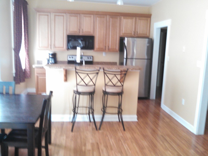 A kitchen with wooden cabinets and a black fridge.