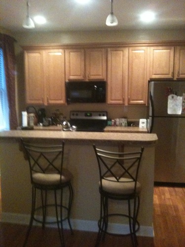 A kitchen with wooden cabinets and a black refrigerator.