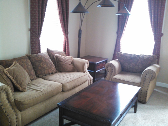 A living room with a brown couch, a brown chair, and a brown coffee table.