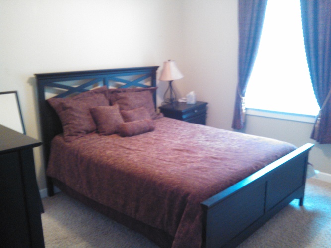 A bed with a red comforter and a blue headboard.