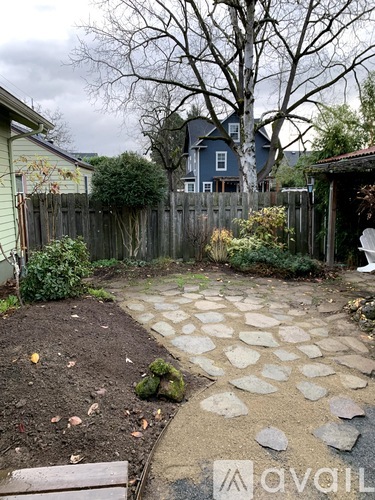 A backyard with a stone walkway and a wooden bench.