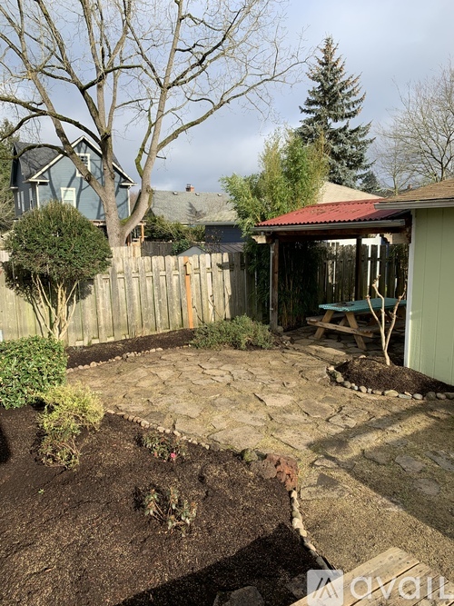 A backyard with a stone patio and a wooden fence.