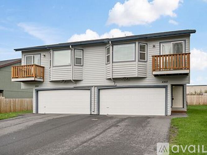 A two-story house with a garage and a balcony on the second floor.