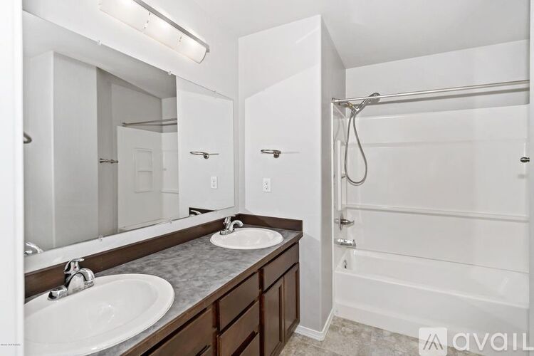 A bathroom with a white shower and a vanity with two sinks.