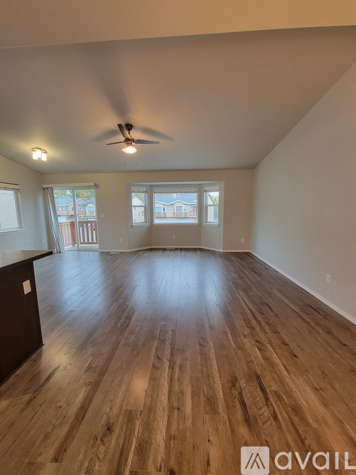 A spacious room with wooden flooring and a ceiling fan.