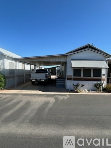 A white house with a carport attached to it.