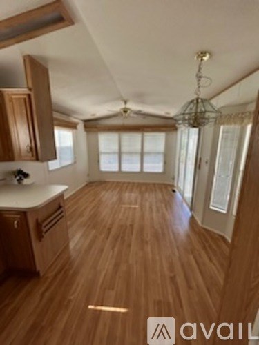 A kitchen with wooden floors and a hanging light fixture.