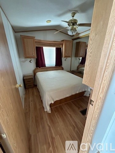 A bedroom with a bed, wooden floors, and a ceiling fan.
