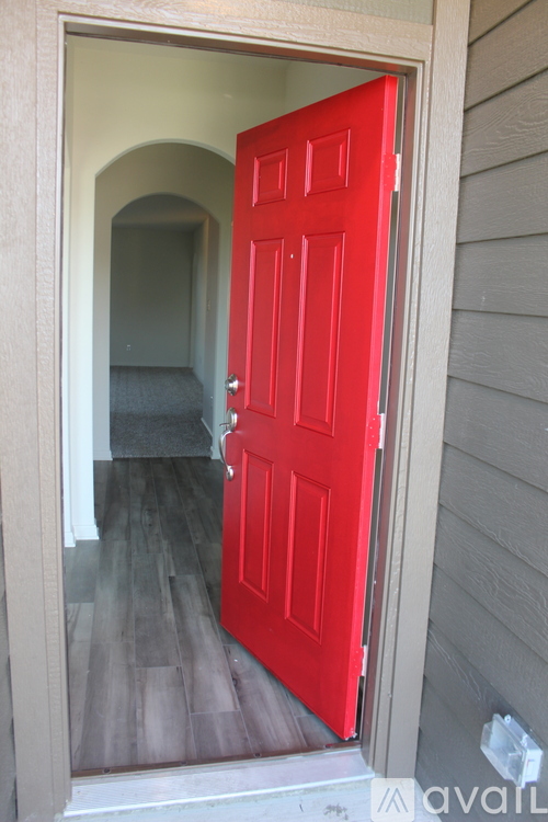 A red door is open to a hallway.