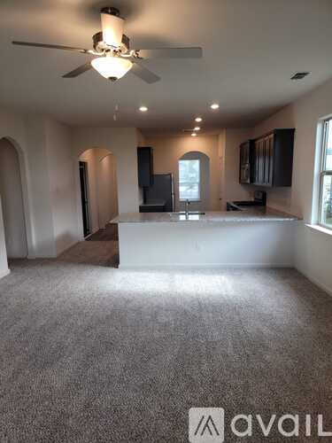 A spacious living room with a ceiling fan and a large window.