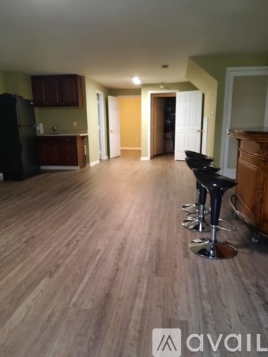 A kitchen with a black fridge and wooden floors.
