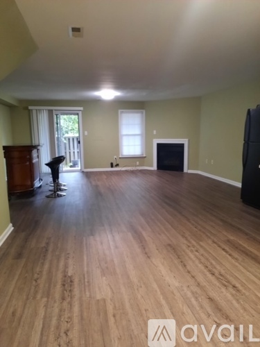 A room with wooden floors and a black refrigerator.