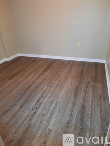 A room with wooden flooring and a wall socket.