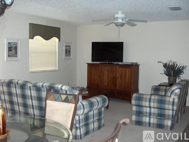 A living room with a checkered couch and a television on a wooden cabinet.