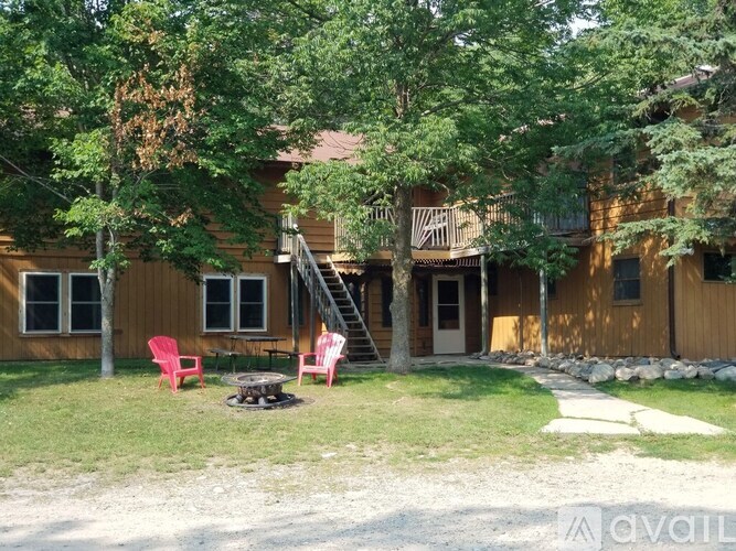 A wooden house with a red chair and a fire pit in front.