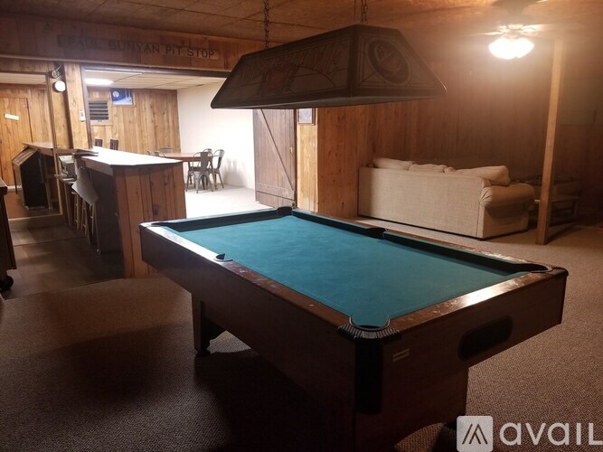 A pool table in a room with a sign that says "Fairbanks Pit Stop".