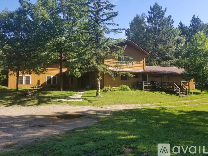 A house with a brown roof and a porch surrounded by trees.