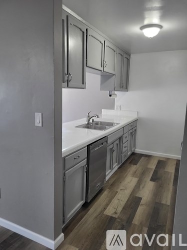 A kitchen with a white sink and wooden floors.