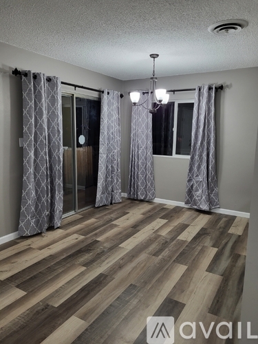 A room with wooden flooring and patterned curtains.