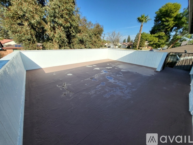 A rooftop pool with a concrete floor and a white wall on the left side.