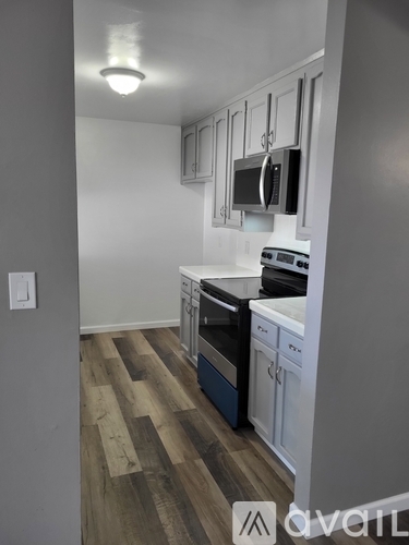 A kitchen with white cabinets and a wooden floor.