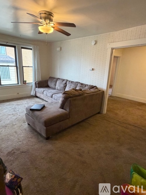 A living room with a grey couch and a ceiling fan.