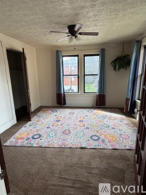 A room with a ceiling fan and a window with curtains.