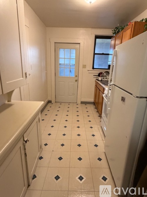 A kitchen with white cabinets and a white fridge.