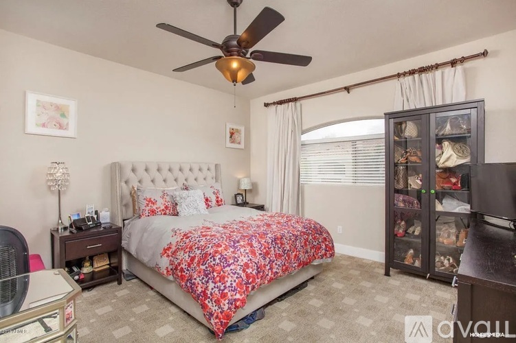 A bedroom with a large bed and a ceiling fan.