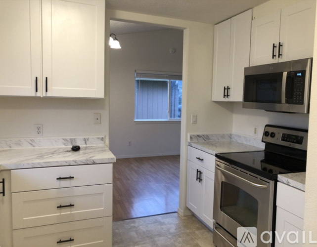 A kitchen with white cabinets and a marble countertop.