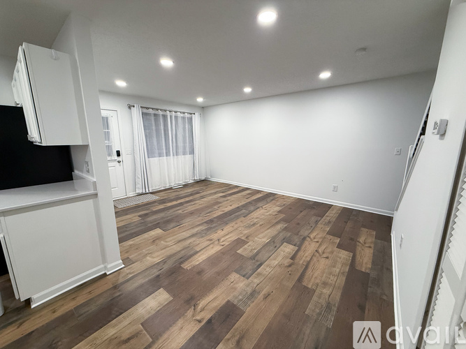 A spacious room with wooden flooring and white walls.