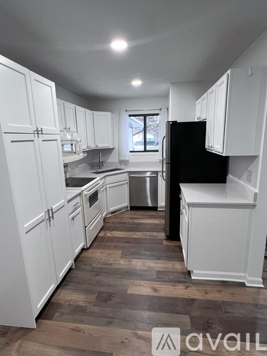 A kitchen with white cabinets and a black refrigerator.