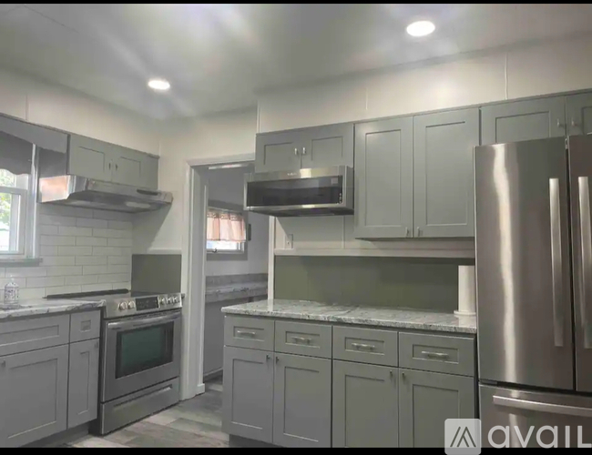 A kitchen with stainless steel appliances and grey cabinets.