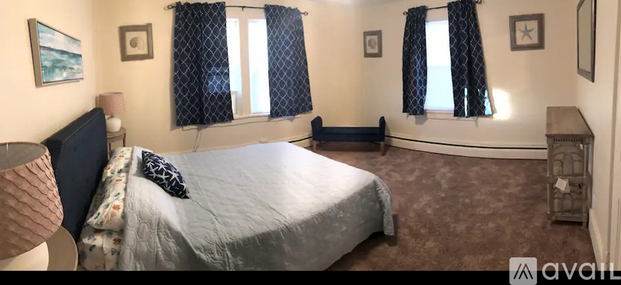 A bedroom with a large bed and a window with curtains.