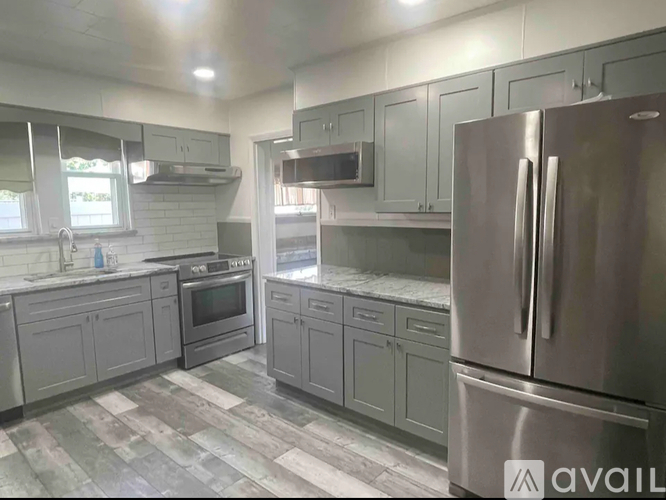 A modern kitchen with a stainless steel refrigerator and grey cabinets.